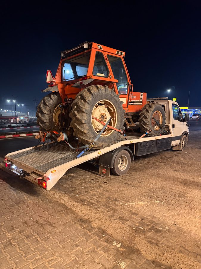 Tractor Fiat transportat pe platformă noaptea