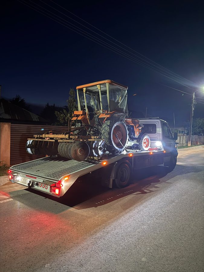 Tractor cu grapă cu discuri transportat pe platformă