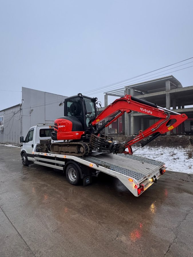Miniexcavator Kubota transportat pe platformă iarna